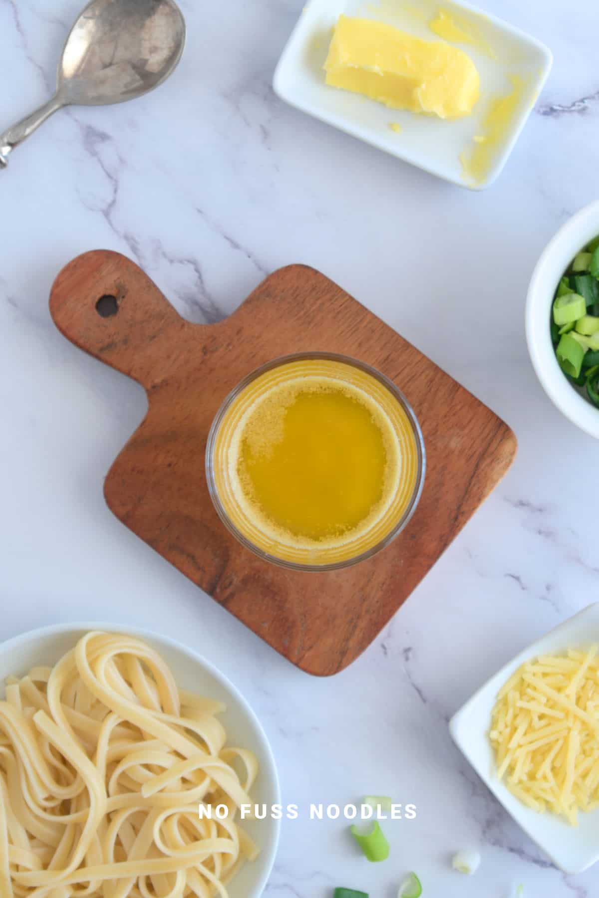 Garlic butter sauce in a glass on a wooden board.