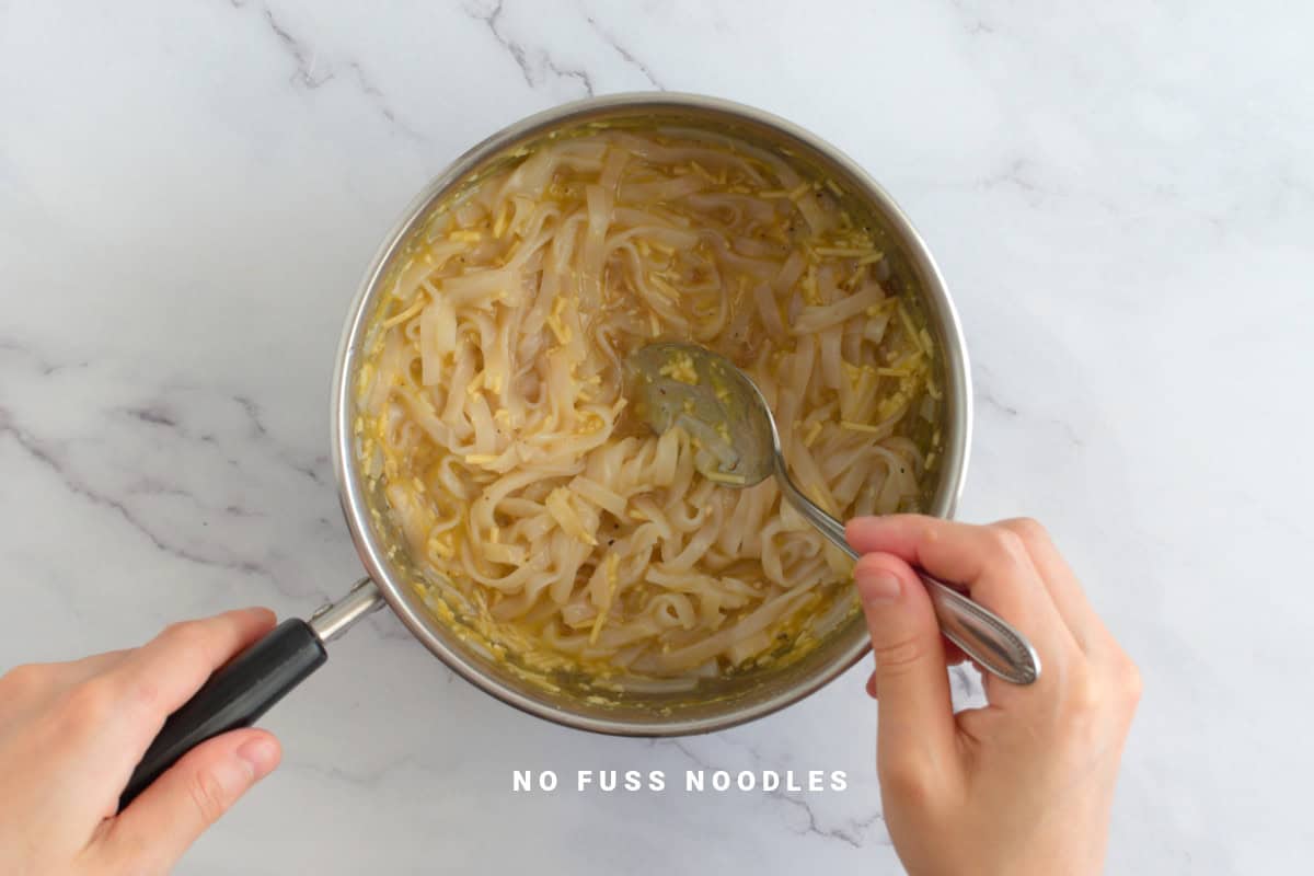Mixing noodles in a saucepan with a spoon.