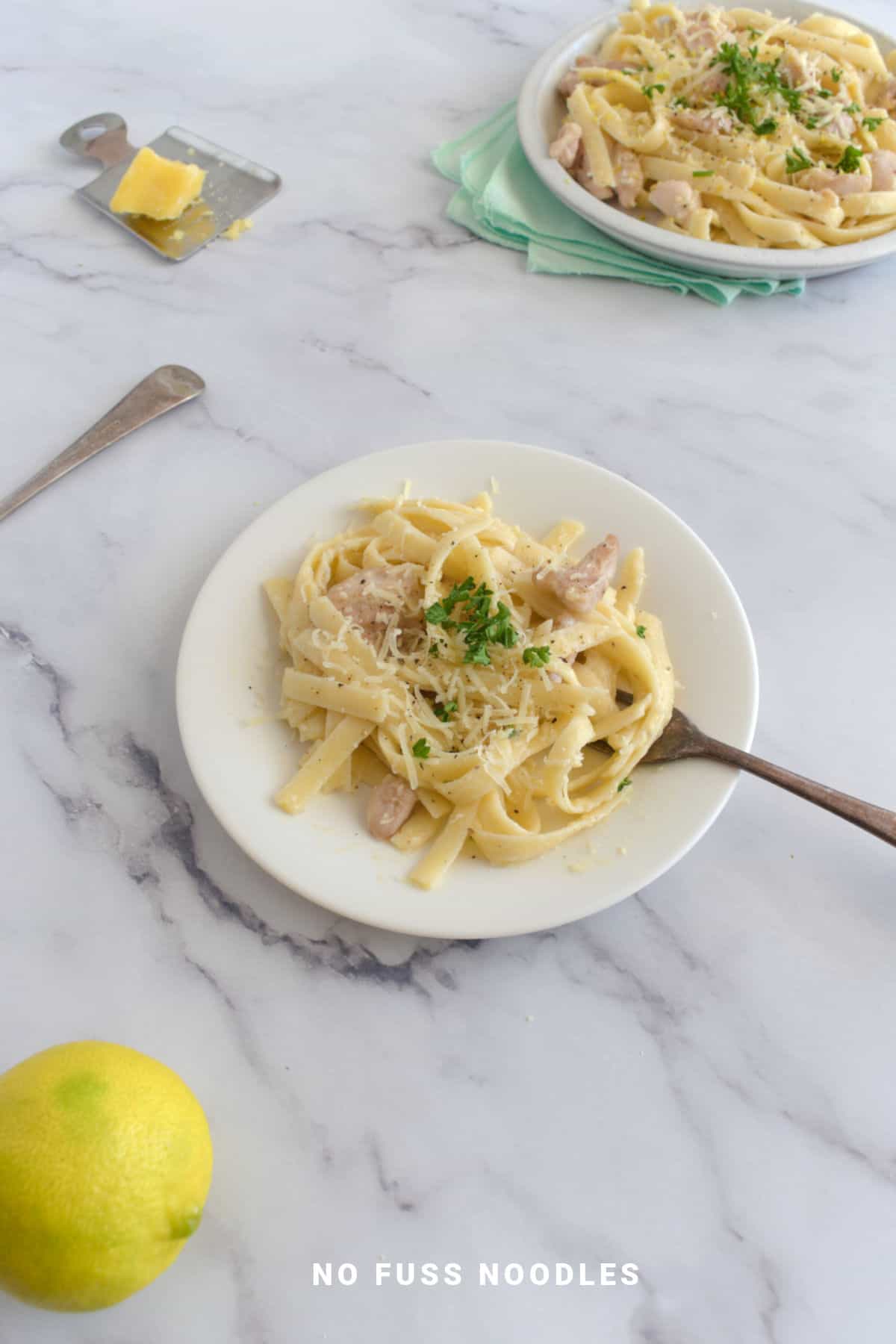 Chicken and garlic noodles on a white plate with a fork.