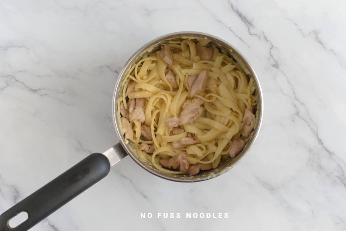 Cooked garlic butter noodles with chicken in a saucepan.