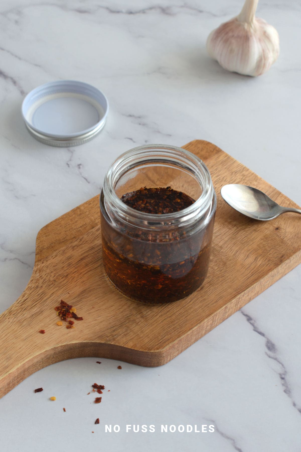Chili garlic oil in a glass jar on a wooden board.
