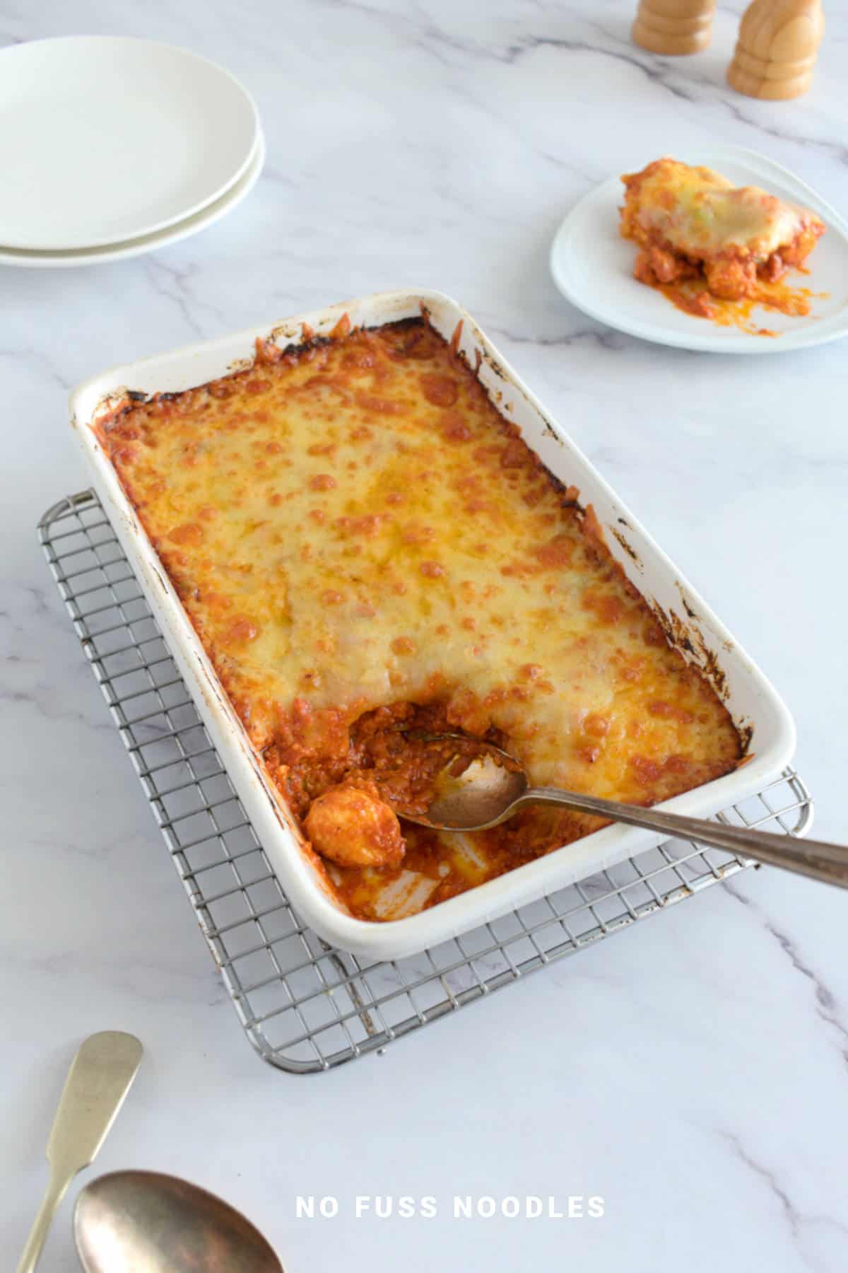 Baked gnocchi in casserole dish with a spoon.