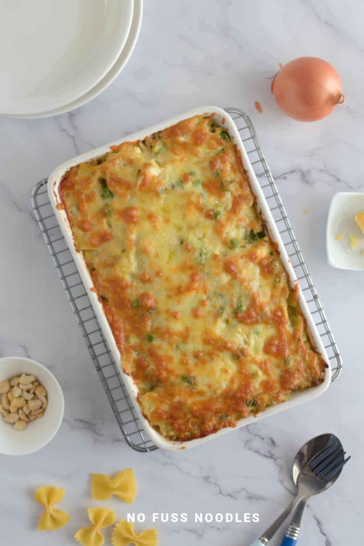 Ricotta pesto pasta bake in a casserole dish on a wire rack.