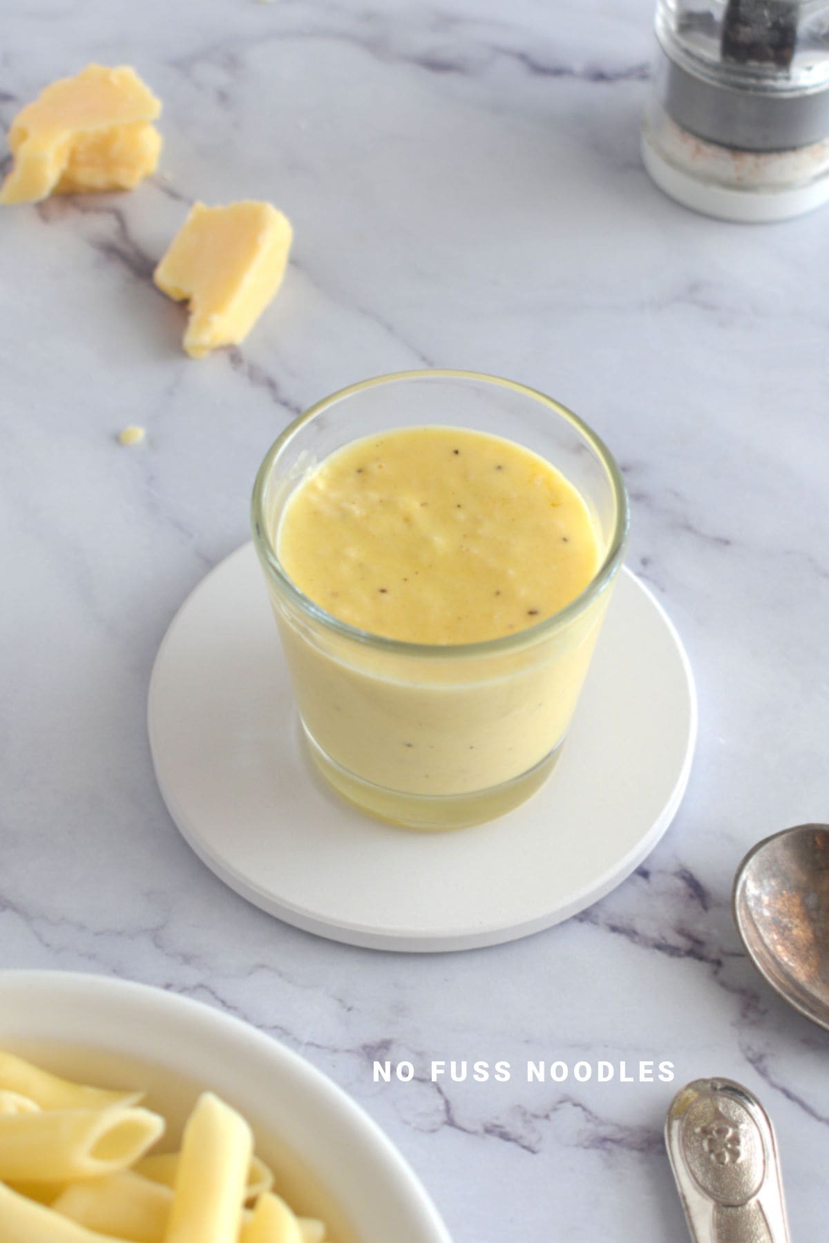 Alfredo sauce in a glass on a coaster.